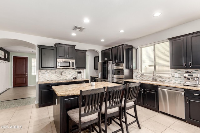 20709 W Delaney Dr, Buckeye, AZ 85396 - kitchen with appliances with stainless steel finishes, arched walkways, decorative backsplash, a kitchen island, and recessed lighting