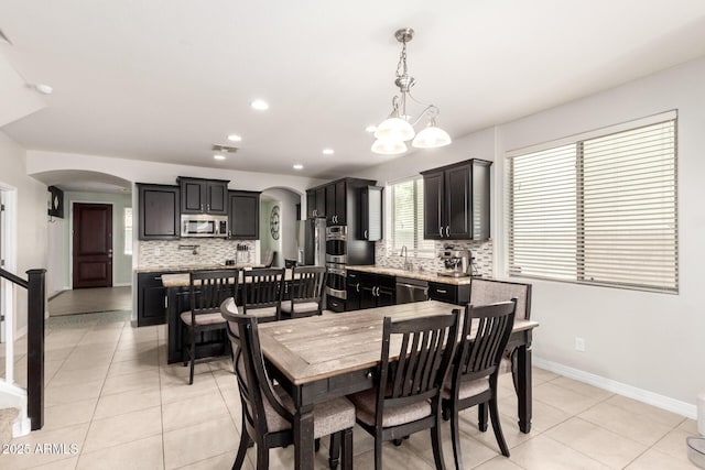 20709 W Delaney Dr, Buckeye, AZ 85396 - dining area with arched walkways, light tile patterned floors, recessed lighting, and a chandelier