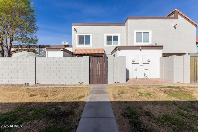 view of property with a tiled roof, a front yard, fence, and stucco siding