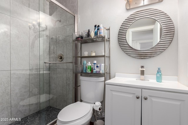 bathroom featuring a textured wall, vanity, a shower stall, and toilet