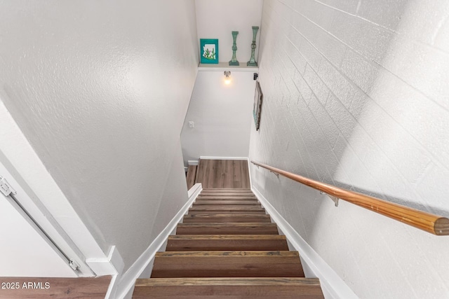 staircase with a textured wall and wood finished floors