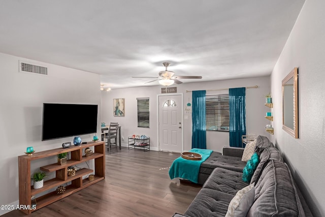 living area with a ceiling fan, dark wood-style flooring, visible vents, and baseboards