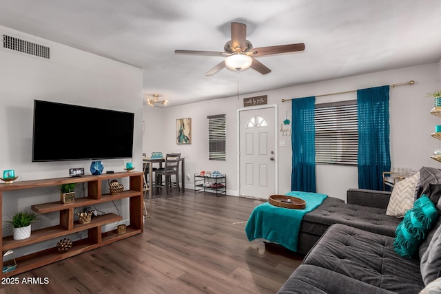 living area featuring baseboards, visible vents, dark wood finished floors, and a ceiling fan