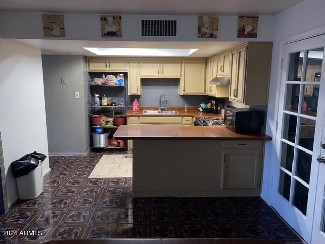 kitchen featuring cream cabinetry, sink, french doors, kitchen peninsula, and dark tile patterned flooring