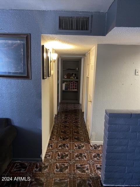 corridor with dark tile patterned flooring and a textured ceiling