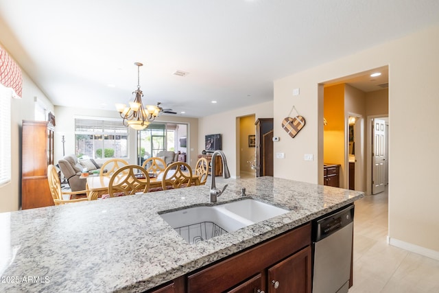 kitchen with decorative light fixtures, dishwasher, sink, and light stone countertops