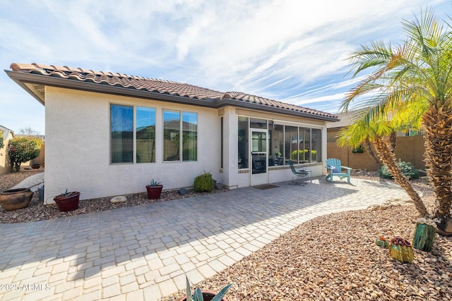 back of property with a sunroom and a patio area