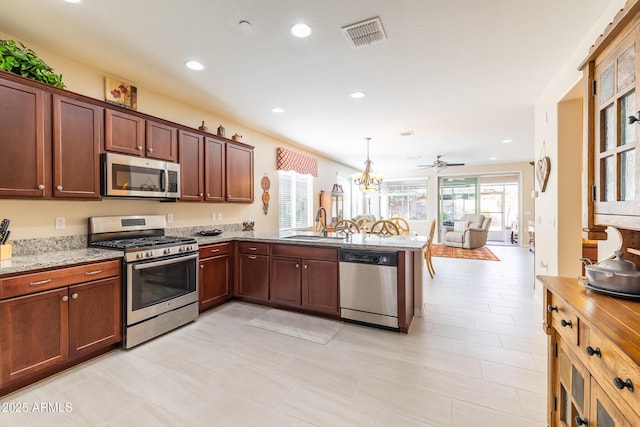 kitchen featuring stainless steel appliances, kitchen peninsula, sink, and plenty of natural light