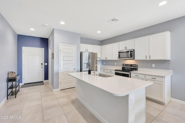 kitchen featuring visible vents, a center island with sink, a sink, baseboards, and stainless steel appliances