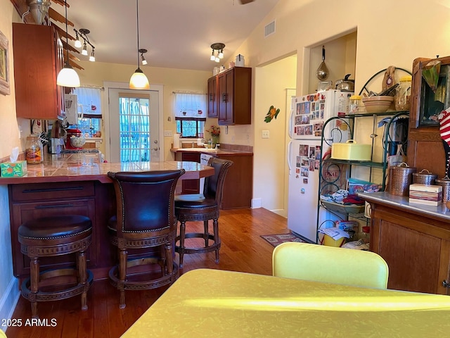 kitchen featuring a breakfast bar area, dark hardwood / wood-style flooring, hanging light fixtures, and lofted ceiling