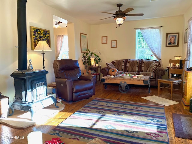 living room featuring hardwood / wood-style flooring, a wood stove, and ceiling fan