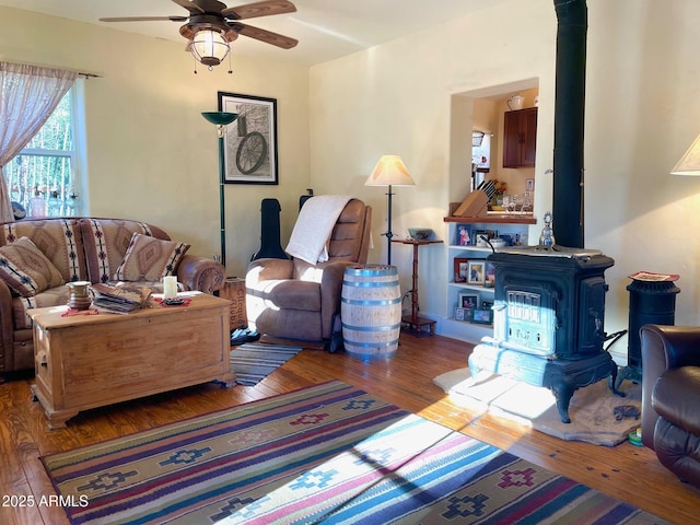 living room featuring a wood stove, ceiling fan, and hardwood / wood-style flooring