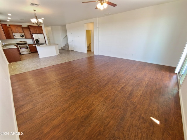 unfurnished living room featuring sink, ceiling fan with notable chandelier, and light hardwood / wood-style floors