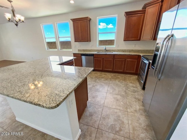 kitchen with sink, appliances with stainless steel finishes, an inviting chandelier, hanging light fixtures, and light stone countertops