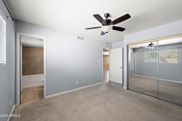 unfurnished bedroom with light colored carpet, ensuite bathroom, a closet, and ceiling fan