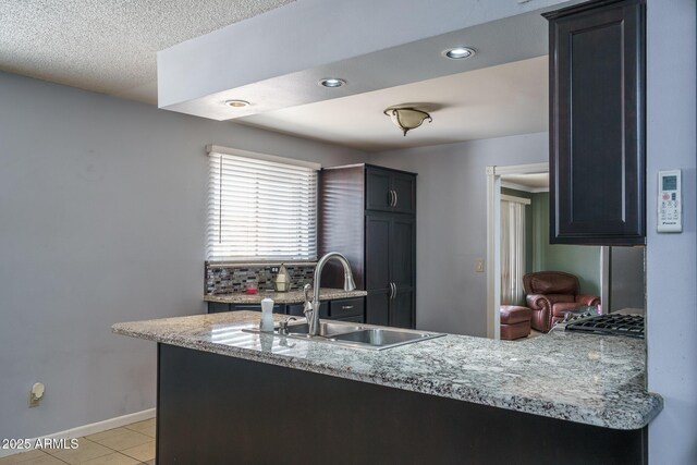 5813 N 39th Ave, Phoenix, AZ 85019 - kitchen featuring a sink, baseboards, light tile patterned floors, backsplash, and a peninsula
