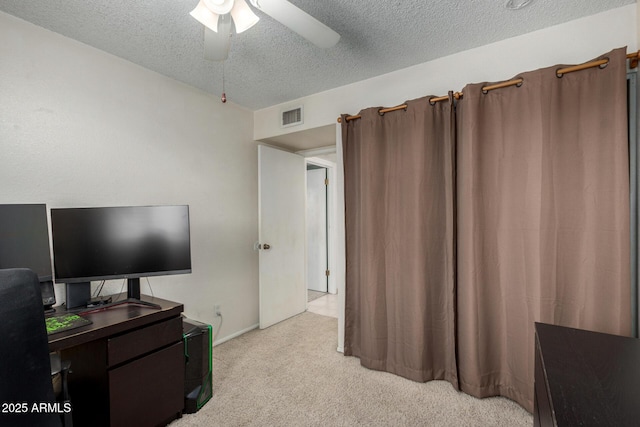 interior space with a textured ceiling, light colored carpet, and ceiling fan