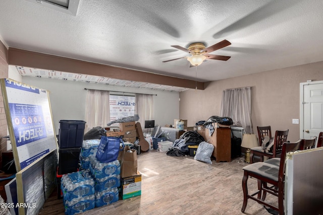 interior space with ceiling fan, wood-type flooring, and a textured ceiling