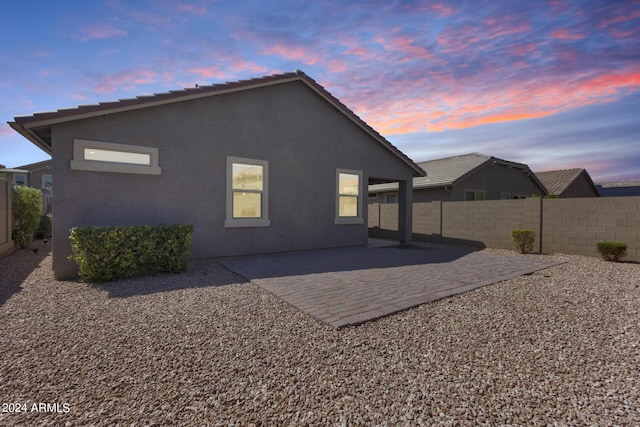 4218 W Palace Station Rd, New River, AZ 85087 - back of property at dusk with a patio area, stucco siding, and a tile roof