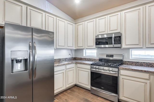 4218 W Palace Station Rd, New River, AZ 85087 - kitchen featuring stainless steel appliances, lofted ceiling, dark wood-style floors, light stone counters, and cream cabinets
