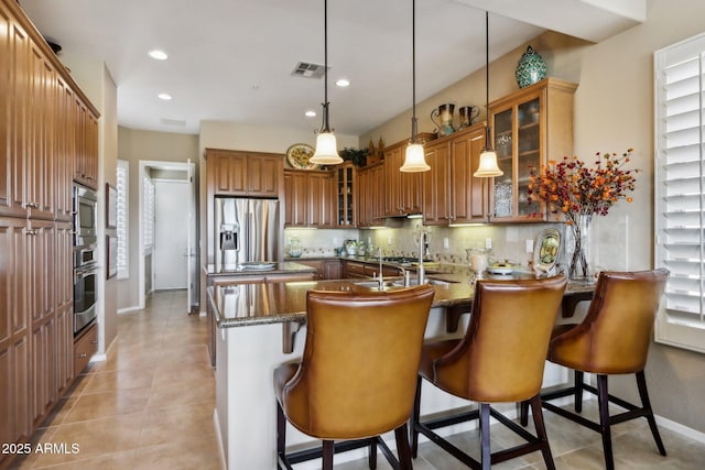 kitchen with a breakfast bar, stone counters, hanging light fixtures, stainless steel appliances, and kitchen peninsula