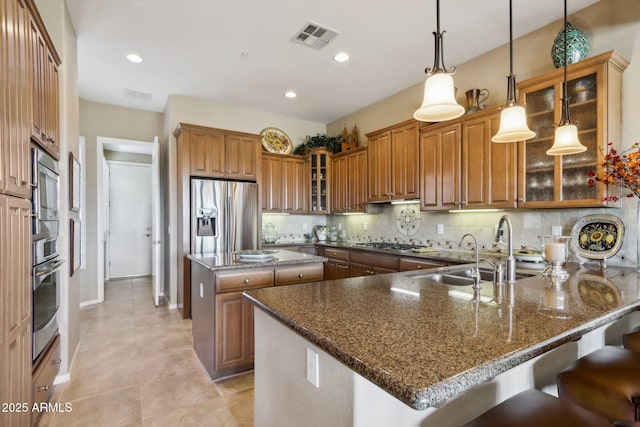 kitchen featuring a breakfast bar, pendant lighting, tasteful backsplash, a center island, and stainless steel appliances