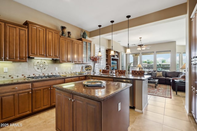 kitchen featuring sink, dark stone countertops, hanging light fixtures, kitchen peninsula, and stainless steel appliances