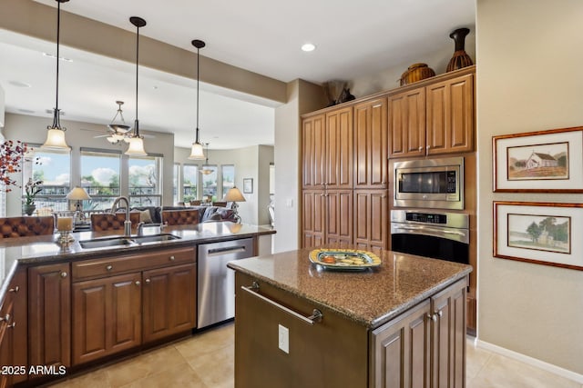 kitchen featuring decorative light fixtures, sink, dark stone counters, a center island, and stainless steel appliances