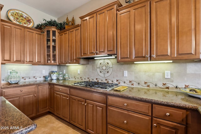 kitchen with dark stone countertops, decorative backsplash, and stainless steel gas stovetop