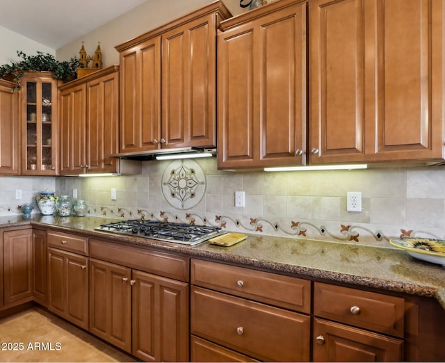 kitchen featuring backsplash, light tile patterned flooring, stainless steel gas stovetop, and stone counters