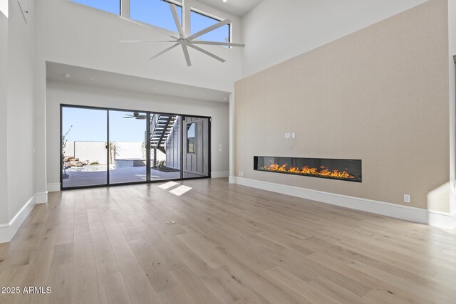8503 S 9th Dr Unit 17, Phoenix, AZ 85041 - unfurnished living room with wood finished floors, a glass covered fireplace, baseboards, and a high ceiling