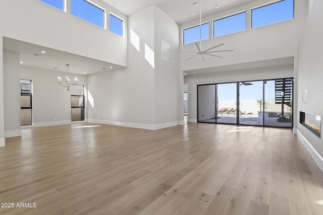 8503 S 9th Dr Unit 17, Phoenix, AZ 85041 - unfurnished living room with a fireplace, a chandelier, light wood finished floors, a towering ceiling, and healthy amount of natural light