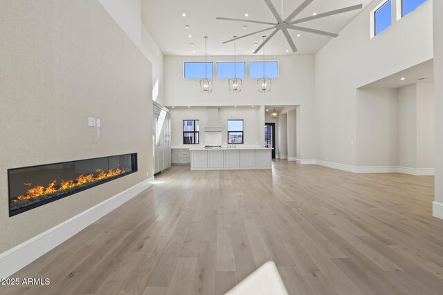 8503 S 9th Dr Unit 17, Phoenix, AZ 85041 - unfurnished living room with a high ceiling, a glass covered fireplace, light wood-type flooring, recessed lighting, and baseboards