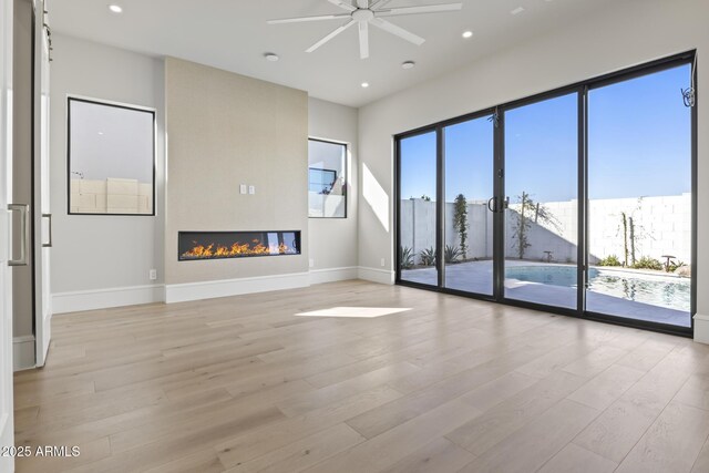 8503 S 9th Dr Unit 17, Phoenix, AZ 85041 - unfurnished living room with light wood-style floors, ceiling fan, recessed lighting, baseboards, and a large fireplace