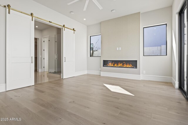 8503 S 9th Dr Unit 17, Phoenix, AZ 85041 - unfurnished living room featuring a barn door, light wood-style flooring, ceiling fan, baseboards, and recessed lighting