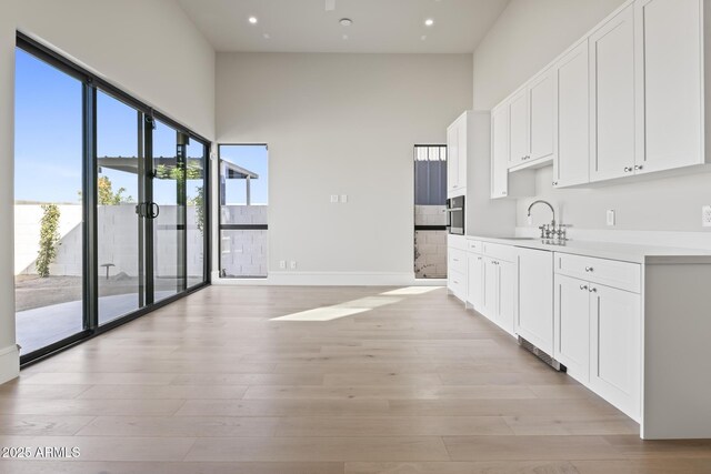 8503 S 9th Dr Unit 17, Phoenix, AZ 85041 - kitchen featuring a sink, a high ceiling, white cabinetry, light wood finished floors, and oven