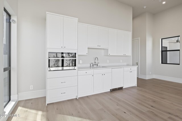 8503 S 9th Dr Unit 17, Phoenix, AZ 85041 - kitchen featuring stainless steel oven, a sink, light wood-style floors, light countertops, and white cabinets