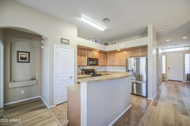 25659 W Forest Grove Ave, Buckeye, AZ 85326 - kitchen featuring black appliances, light countertops, arched walkways, light wood-type flooring, and recessed lighting