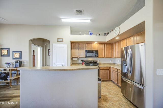25659 W Forest Grove Ave, Buckeye, AZ 85326 - kitchen with black appliances, arched walkways, light countertops, a kitchen island, and light tile patterned floors
