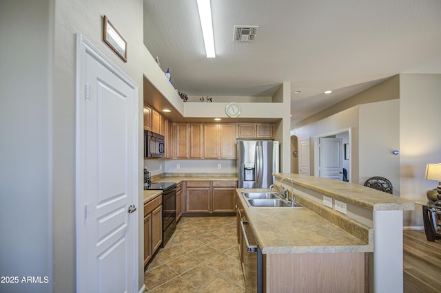 25659 W Forest Grove Ave, Buckeye, AZ 85326 - kitchen with black appliances, a sink, light countertops, a kitchen island with sink, and brown cabinetry