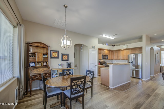 25659 W Forest Grove Ave, Buckeye, AZ 85326 - dining room featuring arched walkways, light wood finished floors, and baseboards