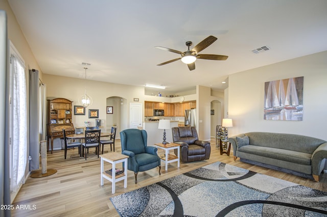 25659 W Forest Grove Ave, Buckeye, AZ 85326 - living area featuring arched walkways, light wood-style floors, and a ceiling fan