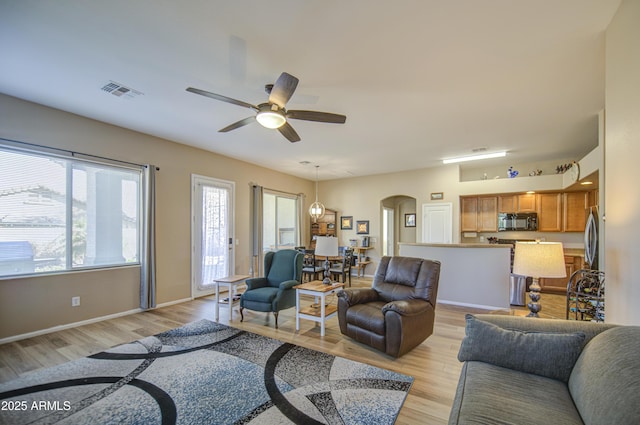 25659 W Forest Grove Ave, Buckeye, AZ 85326 - living room with arched walkways, light wood-type flooring, a ceiling fan, and baseboards
