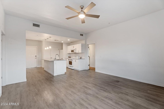 unfurnished living room featuring ceiling fan, sink, and wood-type flooring