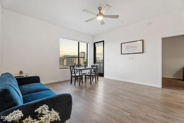 living room with baseboards, wood finished floors, and a ceiling fan