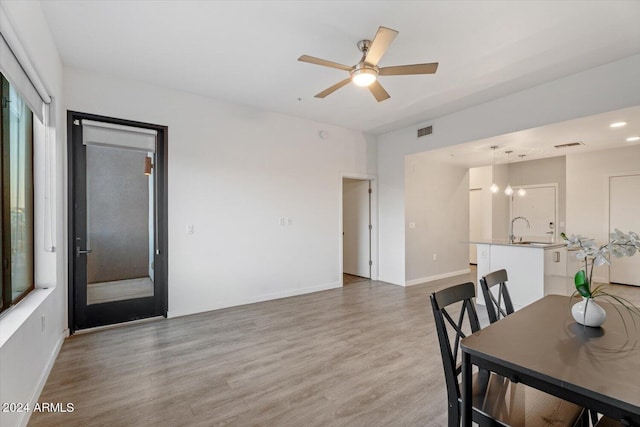 dining room with baseboards, visible vents, light wood-style flooring, and a ceiling fan