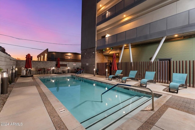 pool at dusk with a patio area