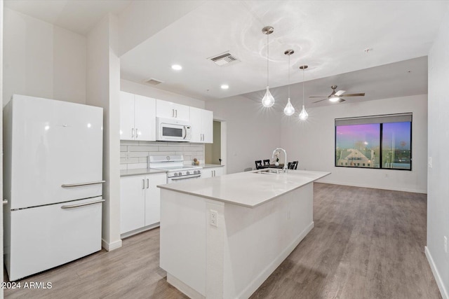 kitchen featuring white appliances, an island with sink, sink, ceiling fan, and white cabinets