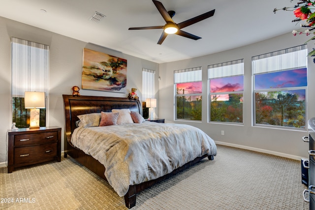 carpeted bedroom featuring multiple windows and ceiling fan