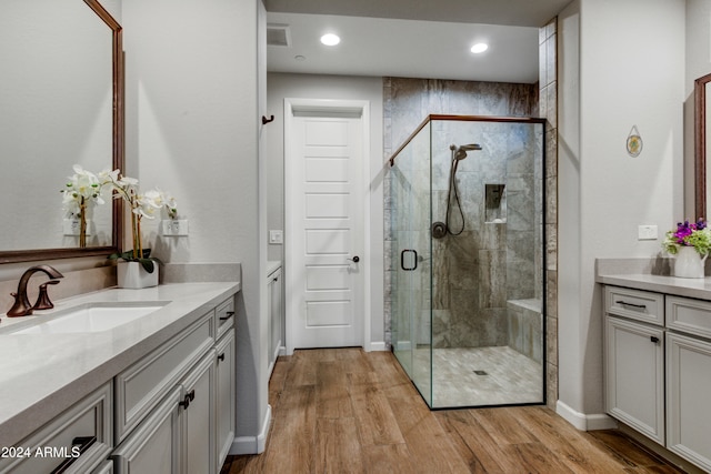 bathroom with walk in shower, vanity, and hardwood / wood-style flooring